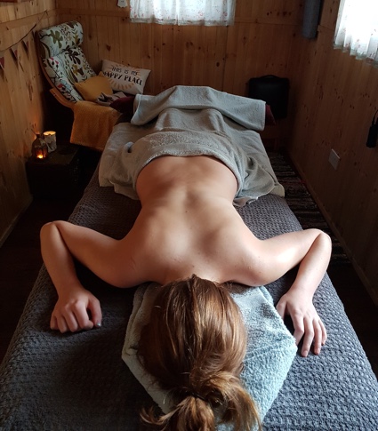 Photograph of a client lying face down on the massage bed receiving a back massage