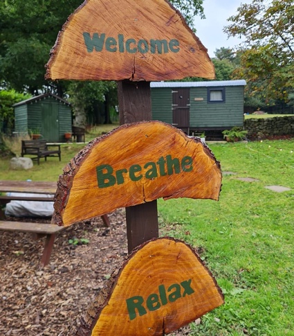 Sign post outside of shepherds rest hut that reads welcome breathe relax